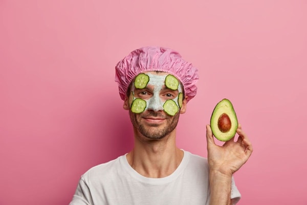man with face mask holding an avocado