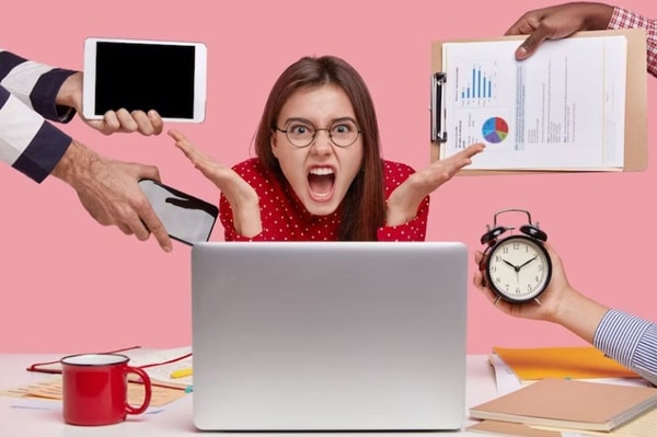 annoyed freelancer gestures in front of laptop computer has much paperwork