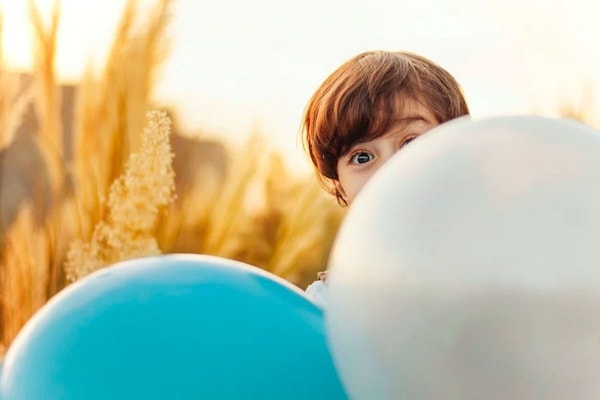 kid hiding behind the balloon